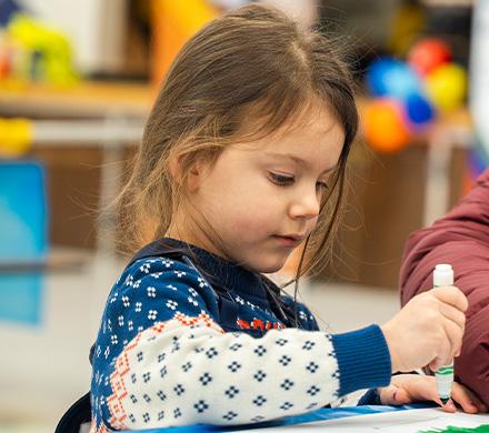 A young child practices their coloring skills in an ASD gymnasium.