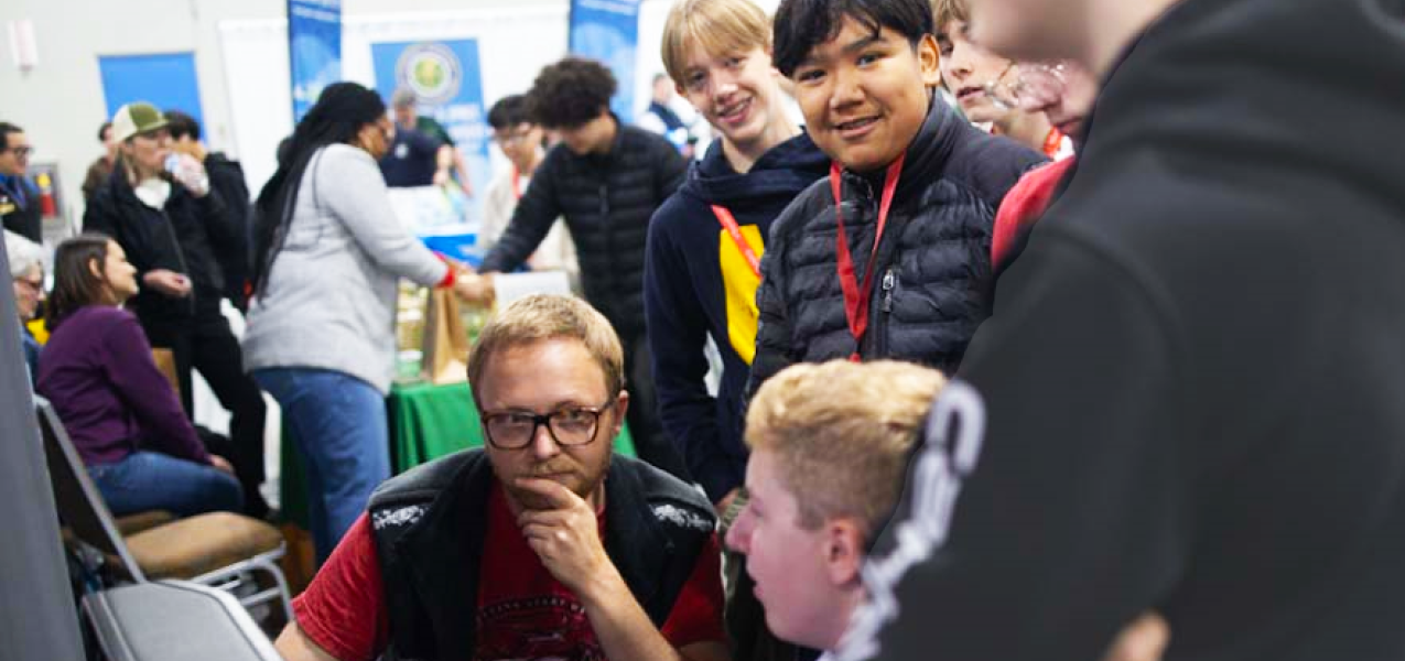 Several high school students talking with company at career expo