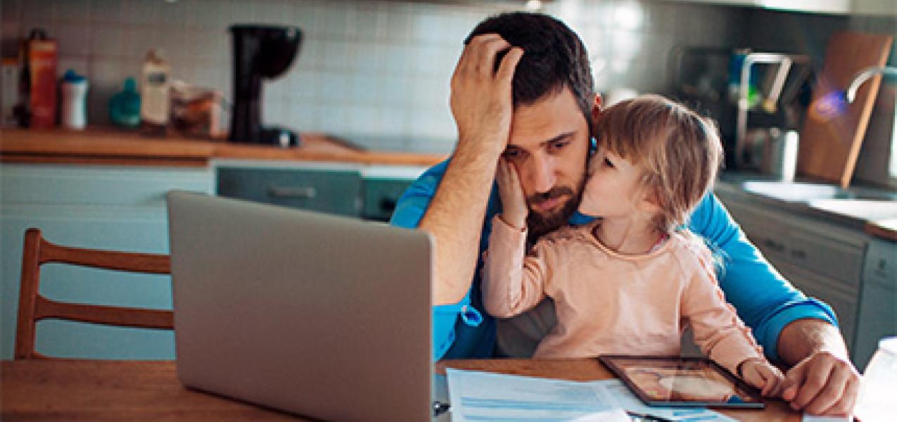 A father who is part of an ALICE household holds his daughter while trying to figure out how to make ends meet.