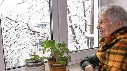 Woman in home looking out window at snow