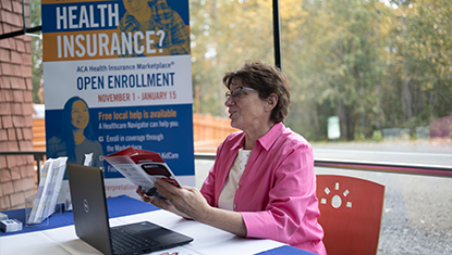 Person sharing a brochure at an event table.